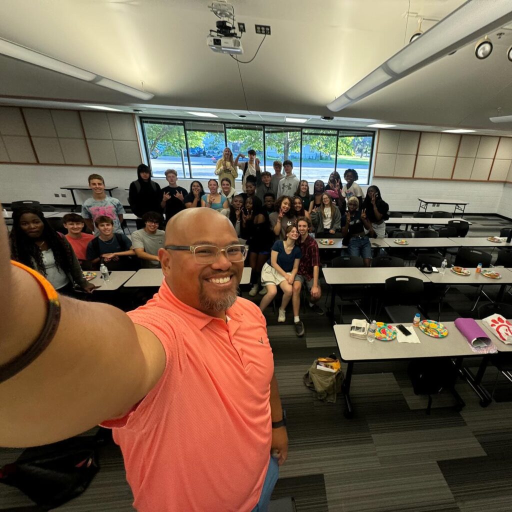 Pastor Phil Santillan taking a selfie with a room full of students at Bibles & Breakfast