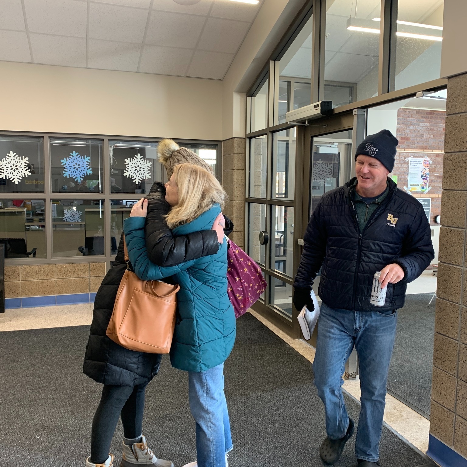 Welcome team members greeting people with hugs at the school doors on a Sunday at Clarity Church